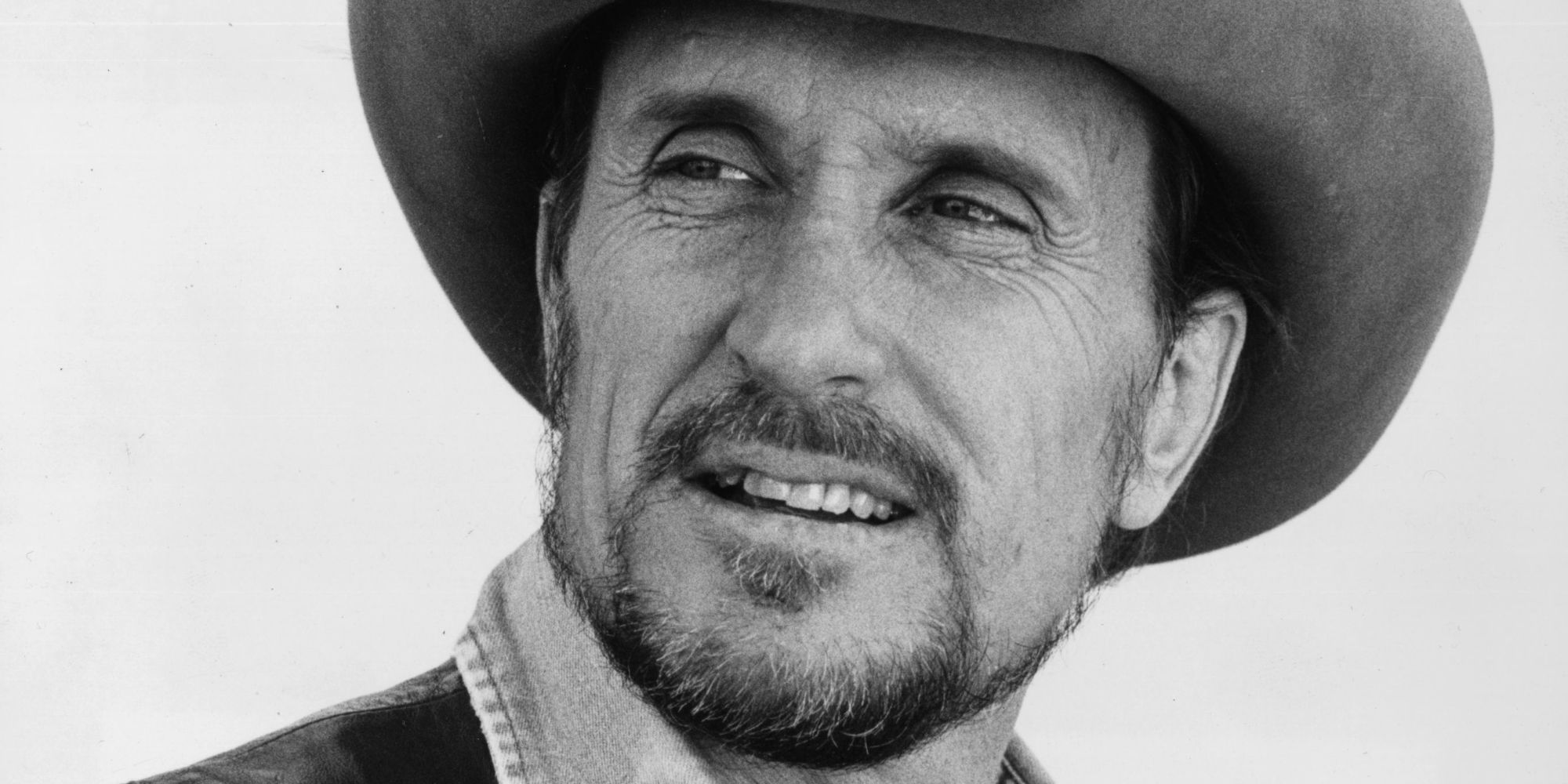 Close up of Robert Duvall as Mac Sledge, wearing a cowboy hat and smiling faintly in Tender Mercies