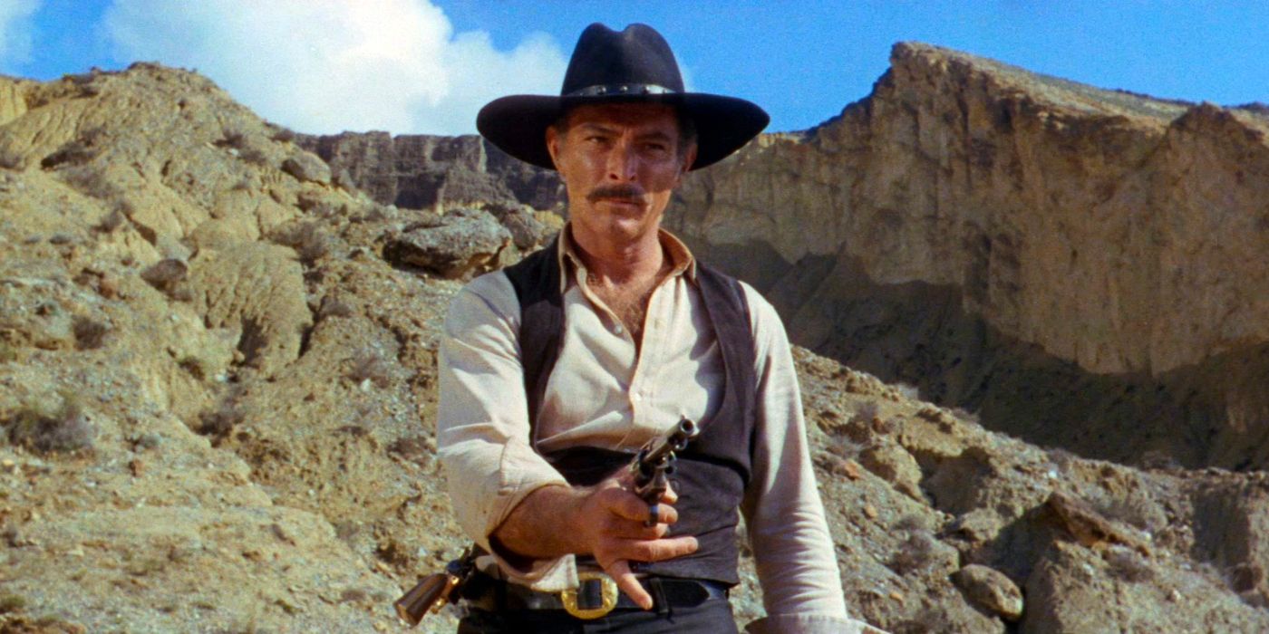 Lee Van Cleef stands in a rocky valley, aiming a pistol in The Big Gundown