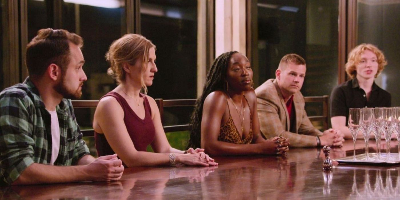 The cast of &lsquo;The Trust: A Game of Greed&rsquo; Season 1 sit at a long table during a Trust Ceremony.