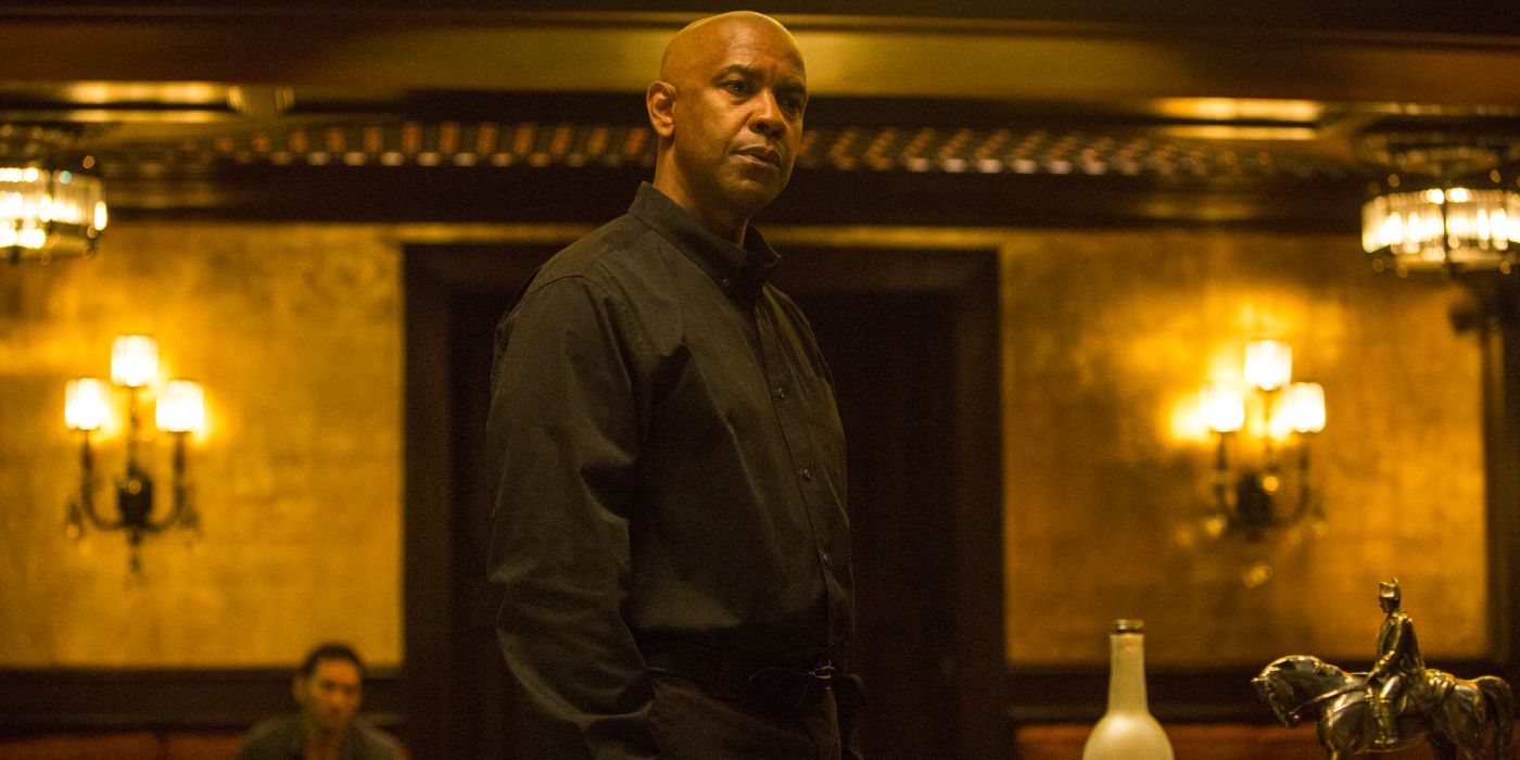 A retired hitman in a black shirt stands in a decadent room.