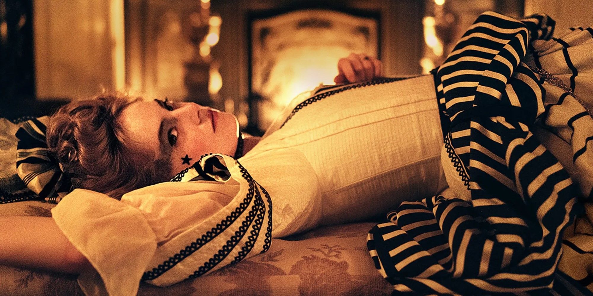 Emma Stone as Abigail Masham, lying in front of a fireplace and smiling slightly in The Favourite