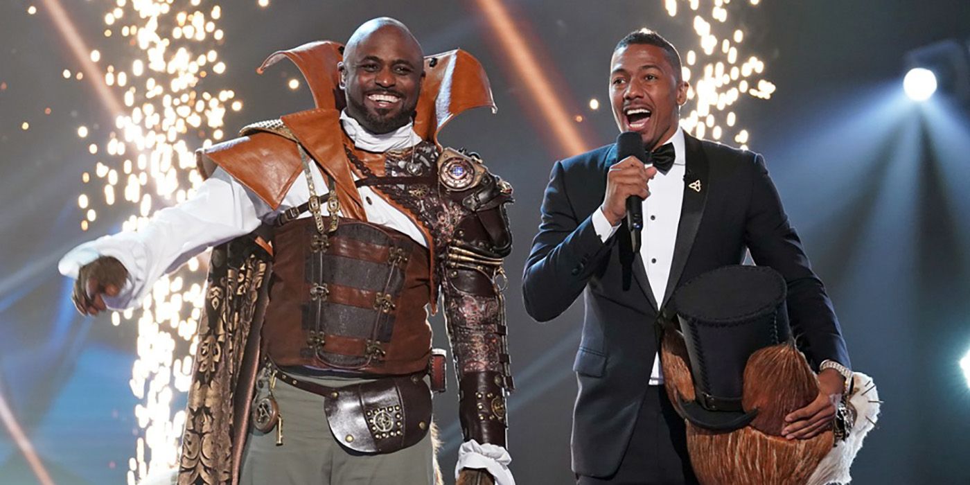 Wayne Brady standing beside Nick Cannon dressed as fox on The Masked Singer.