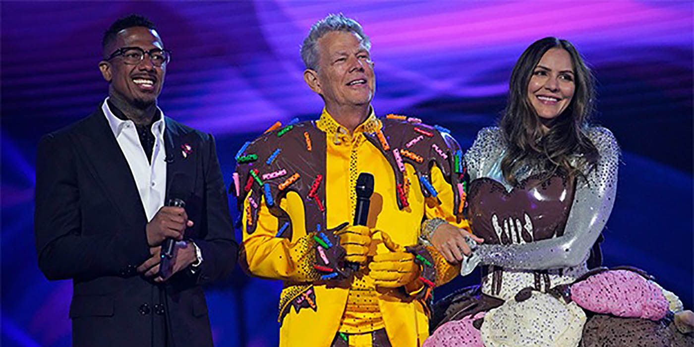 Nick Cannon on stage with David Foster and Katherine McPhee in costumes on The Masked Singer.