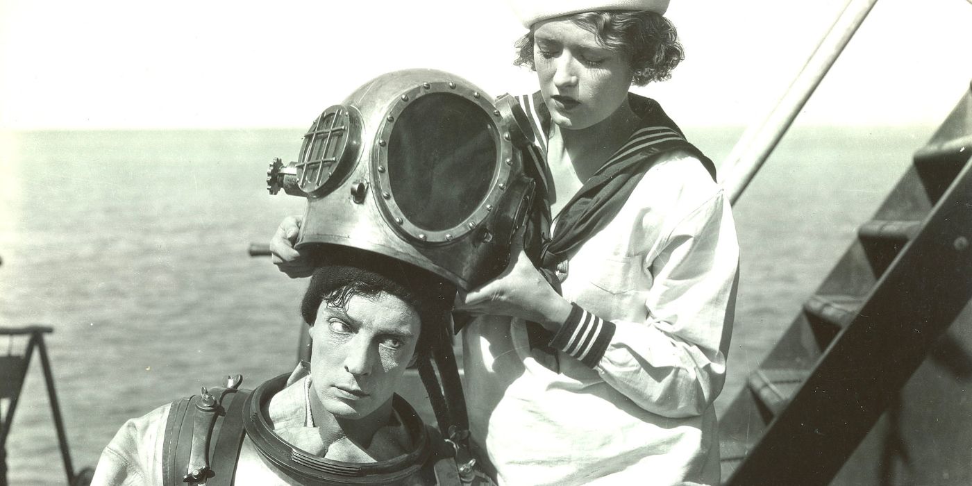 A sailing woman helps a man dress into a diving costume on board a boat out at sea.