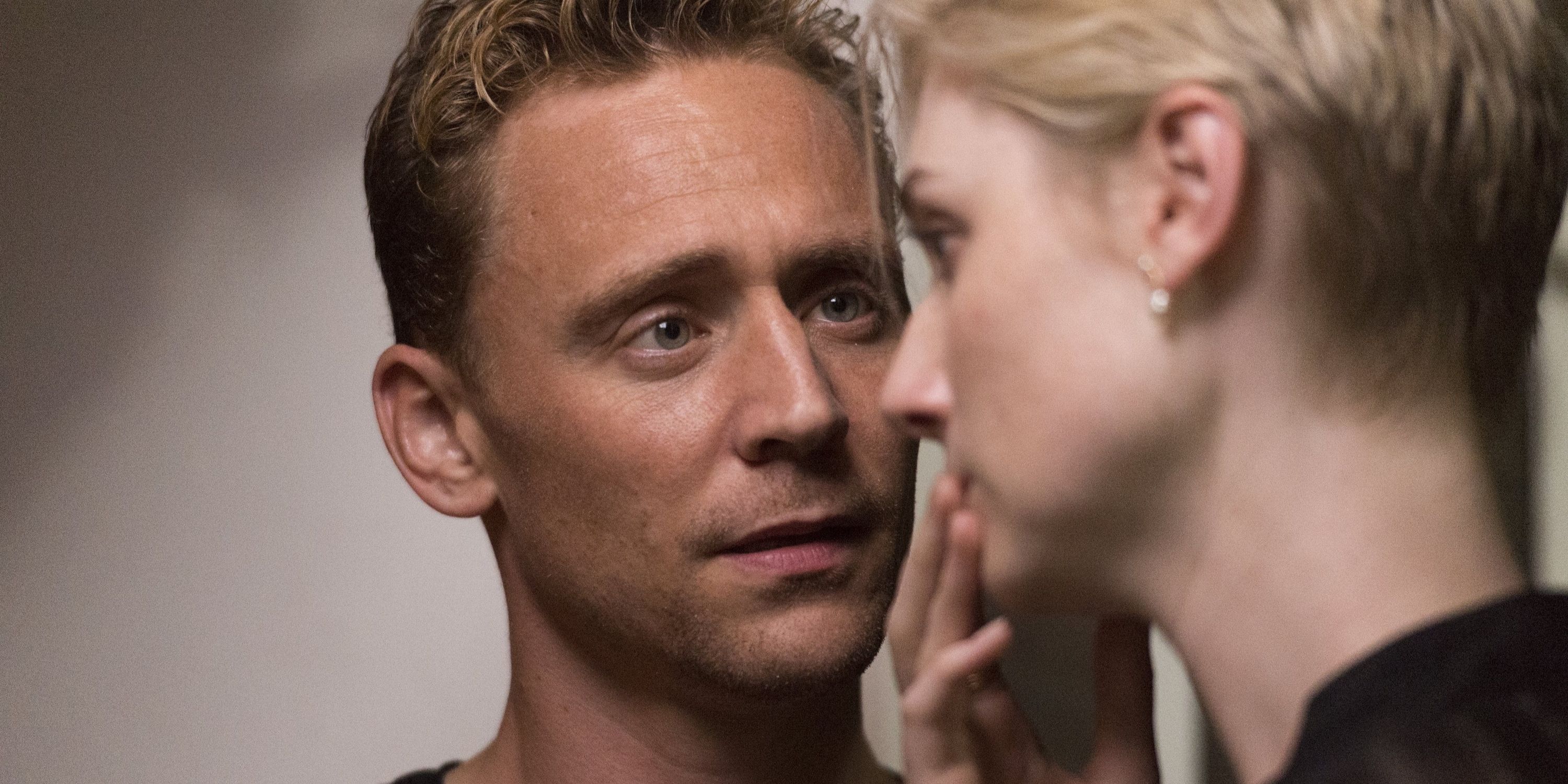A close up of Jonathan Pine, played by Tom Hiddleston, staring intensely at Jed Marshall, played by Elizabeth Debicki, holding her hand to her mouth in The Night Manager