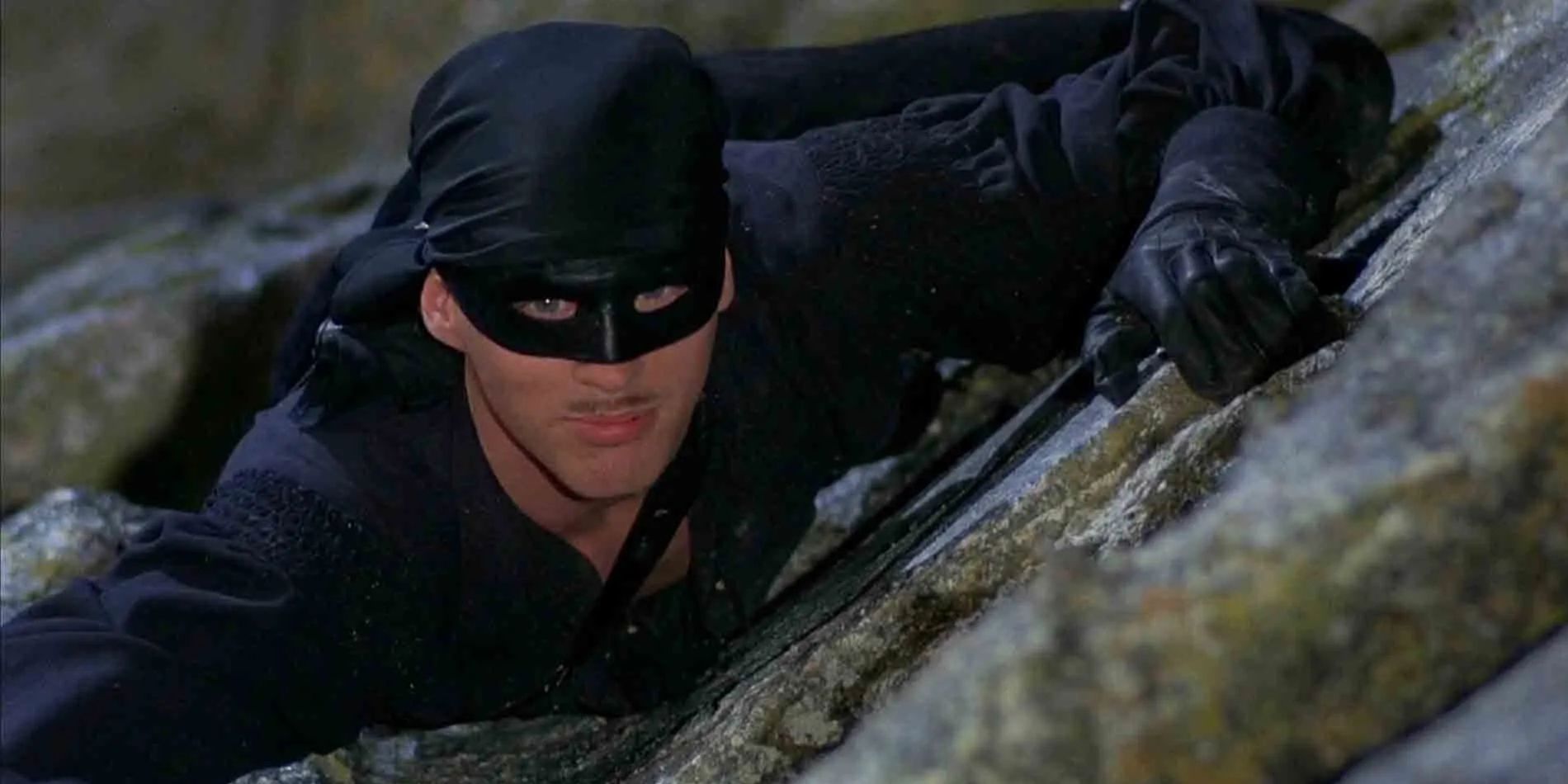 Westley (Cary Elwes) wearing a black mask and climbing the Cliffs of Insanity in 'The Princess Bride'