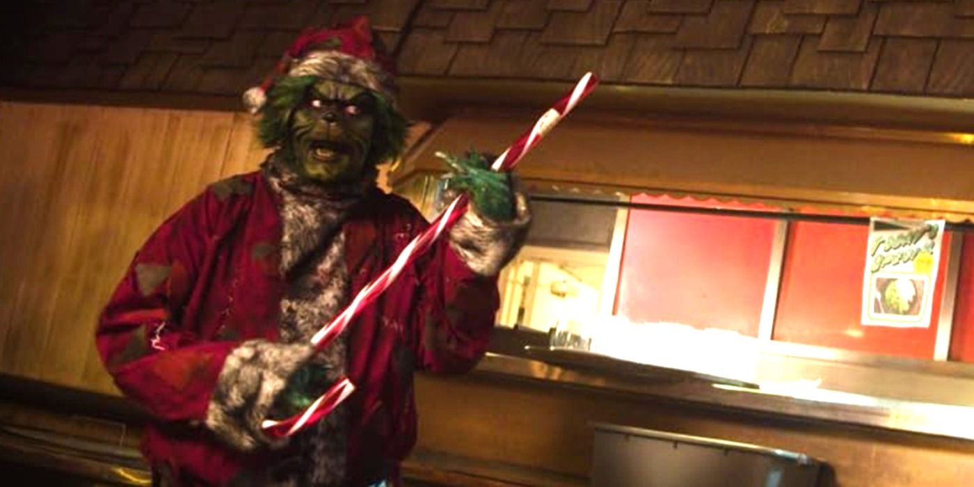 David Howard Thornton as The Grinch dressed as Santa holding a candy cane in The Mean One