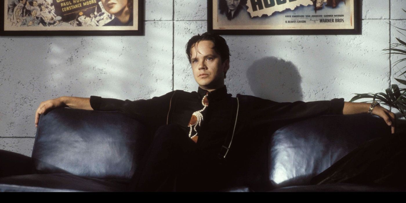 Tim Robbins as Griffin Mill, sitting with his arms spread out on a couch in The Player