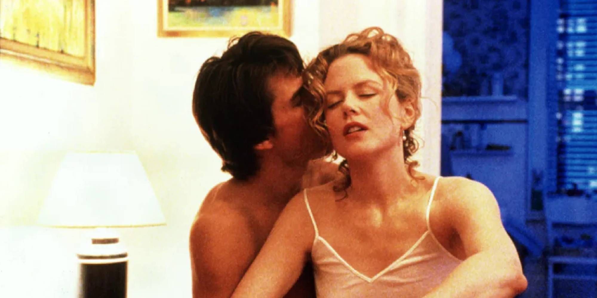 Tom Cruise kissing Nicole Kidman while the two sit in bed in Eyes Wide Shut