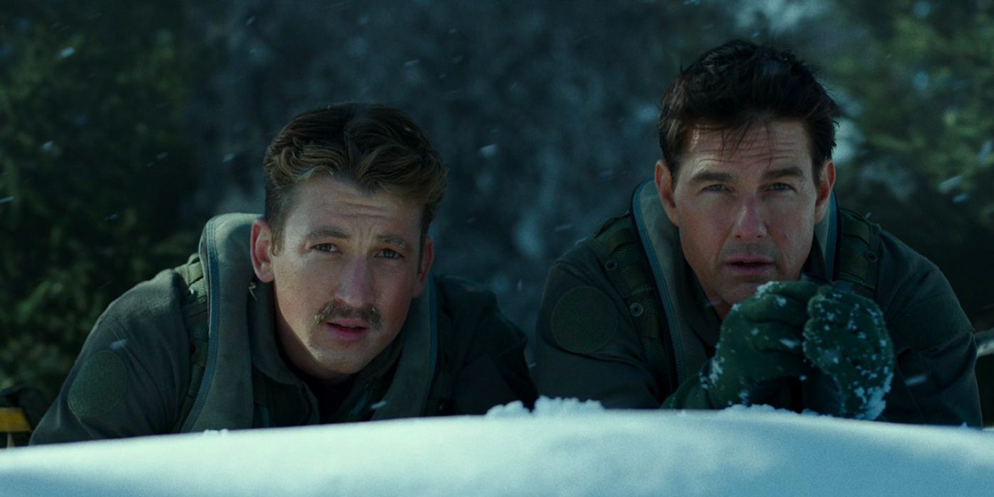 Rooster (Miles Teller) y Maverick (Tom Cruise) se agachan en la nieve para explorar una base aérea enemiga en Top Gun: Maverick.