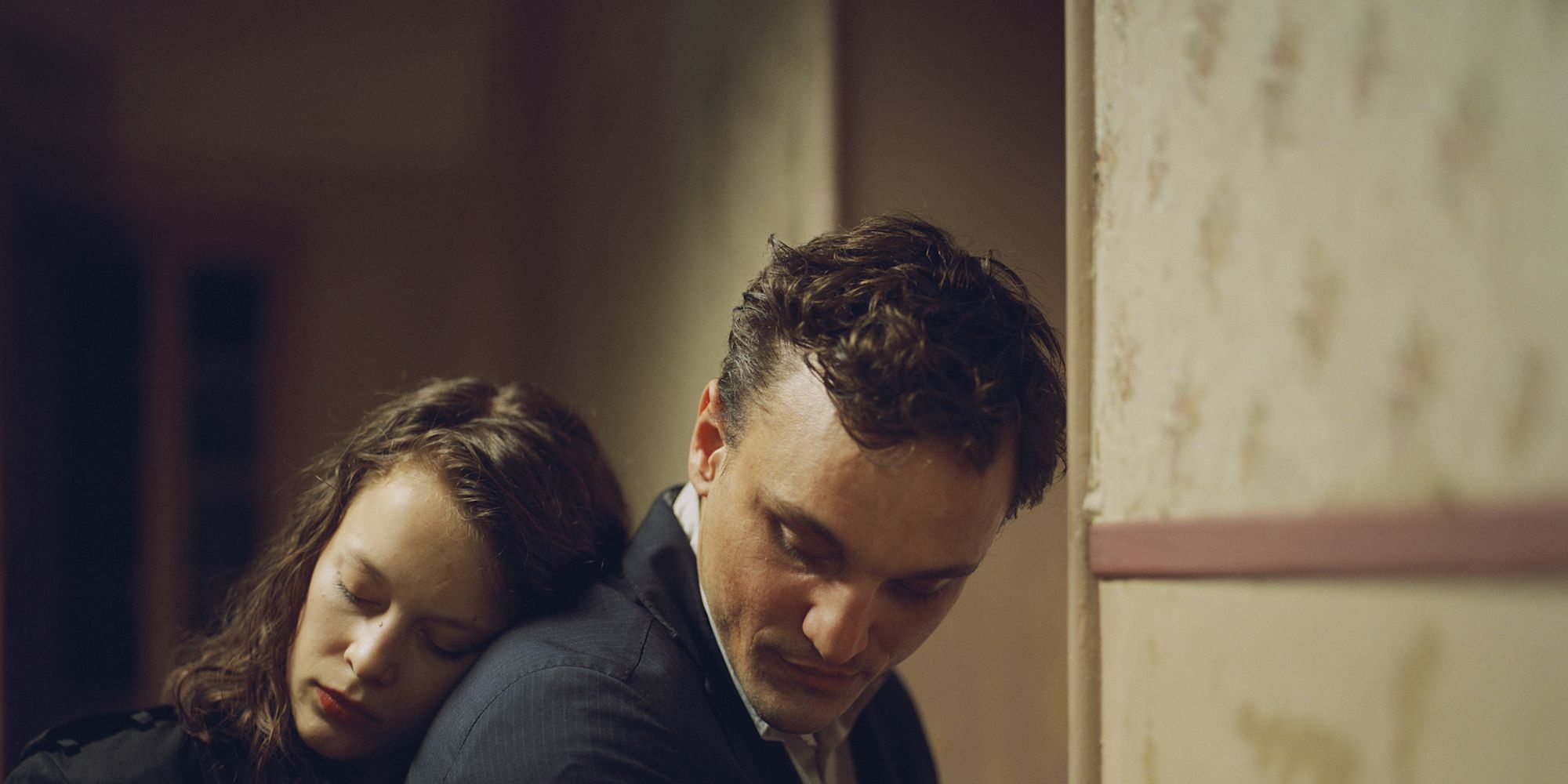 A woman leaning on a man's back in the film Transit 2018