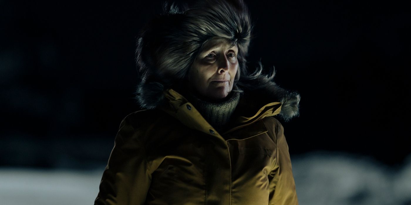 Fiona Shaw standing in the dark winter night wearing a furry coat in True Detective: Night Country