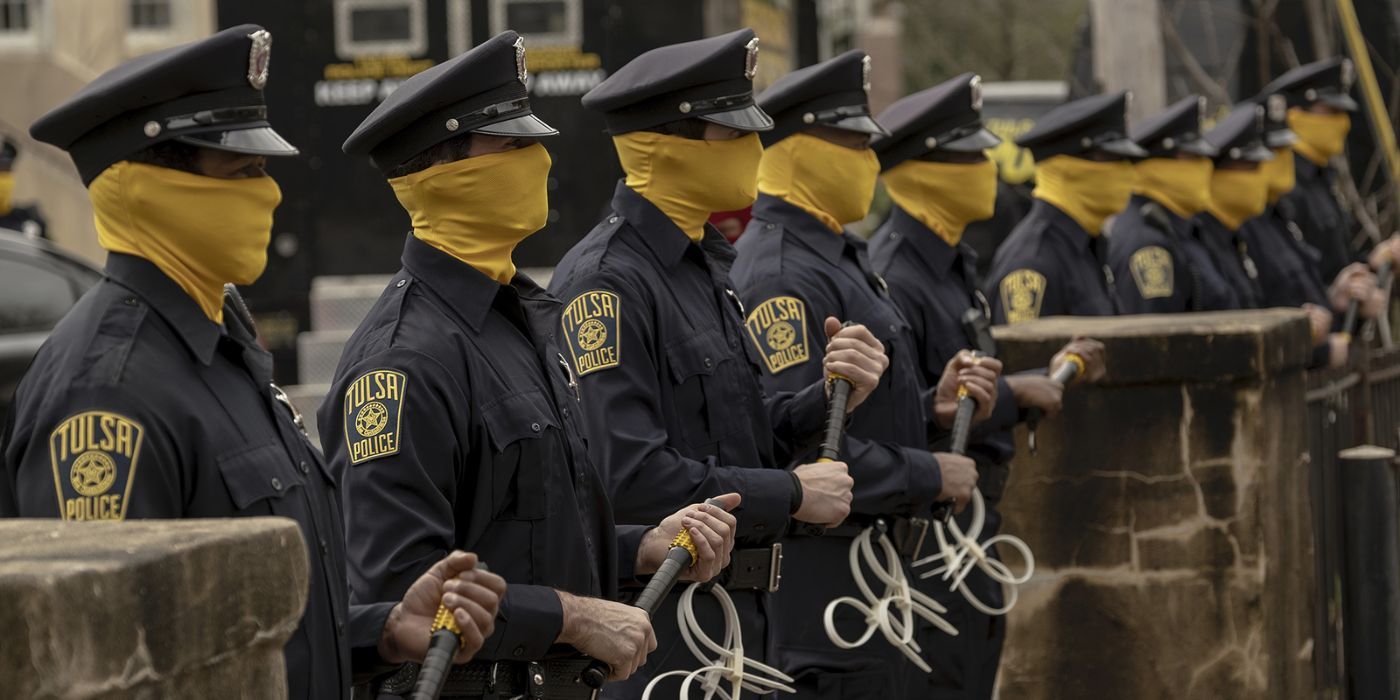 Cops with yellow masks up to their noses, forming a line, brandishing clubs