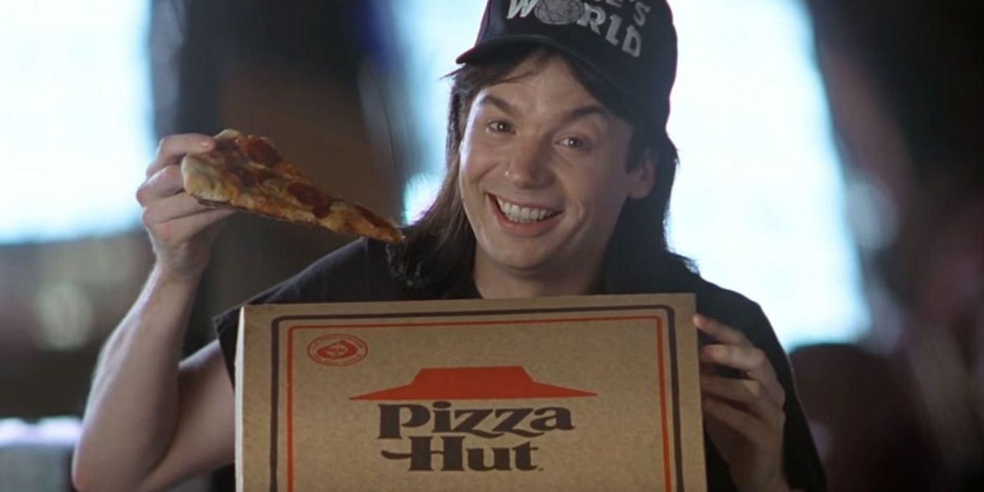 Wayne (Mike Myers) holding up a slice of Pizza Hut pizza in Wayne's World