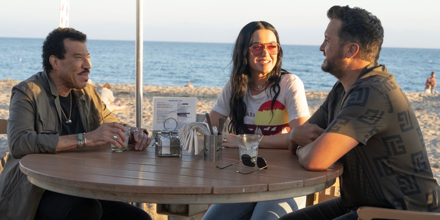 Lionel Richie, Katy Perry, and Luke Bryan sitting at a table on the beach in American Idol Season 22.