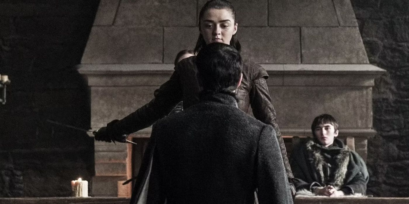 Maise Williams as Arya Stark holding her sword at a man kneeling with Bran Stark in the background