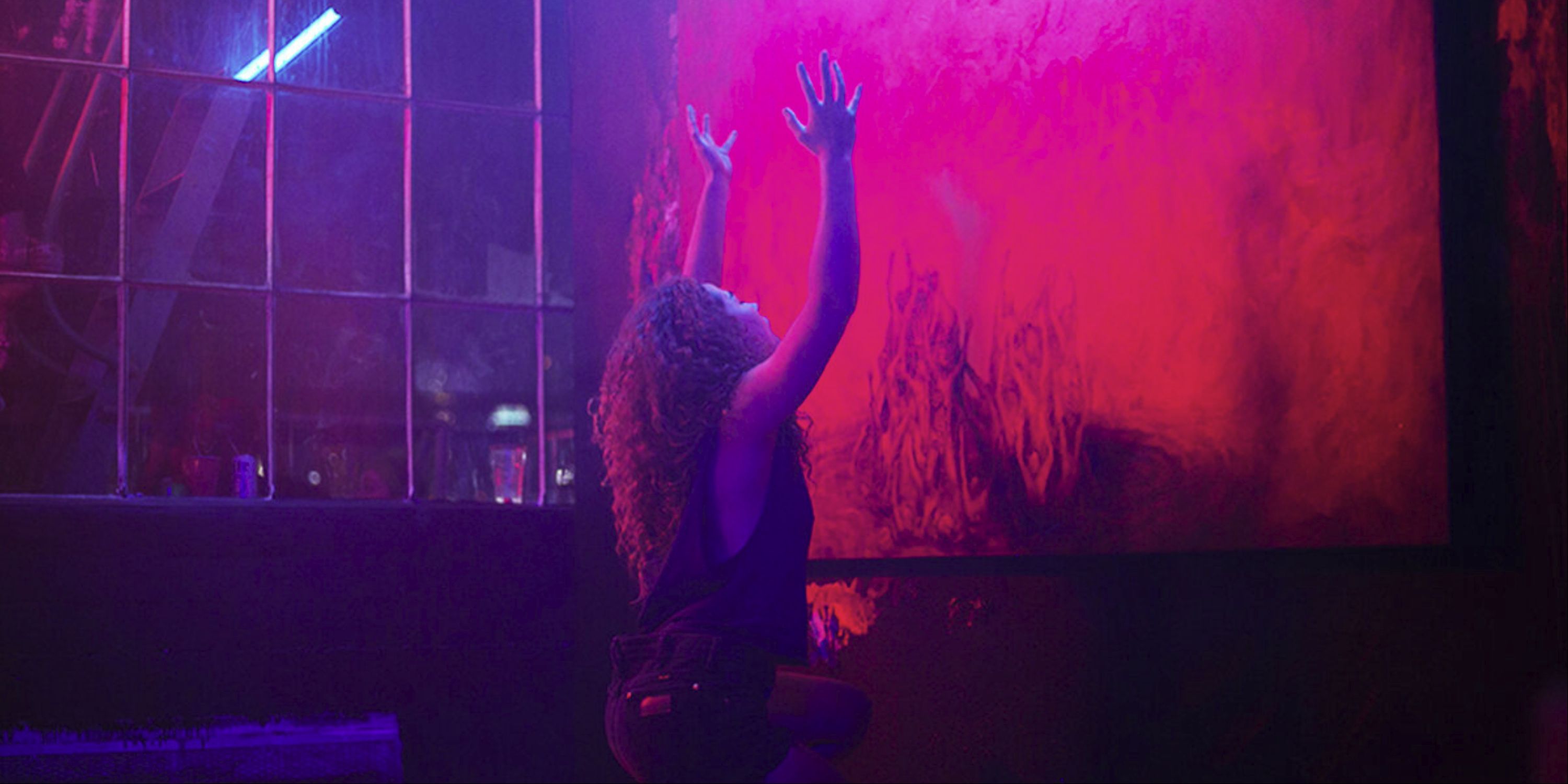 Dora Madison Burge as Dezzy praying to a red wall in Bliss