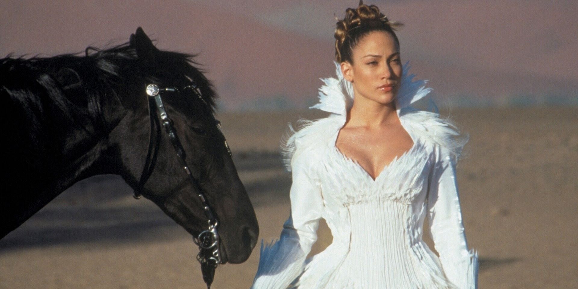 A woman in a white feather gown beside a black horse in the desrt in The Cell