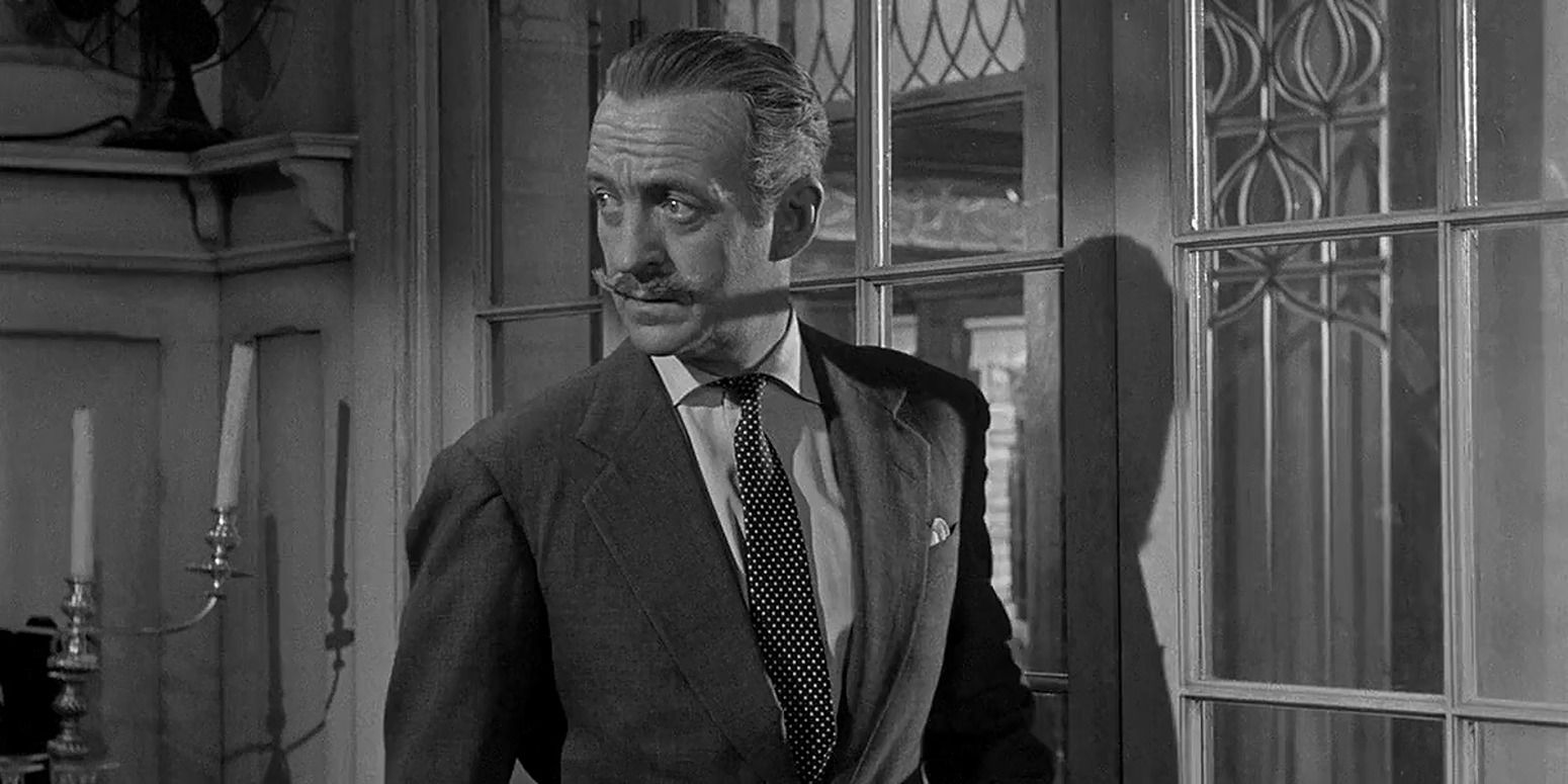 in black and white, man in thick mustache and suit looks back before opening glass door