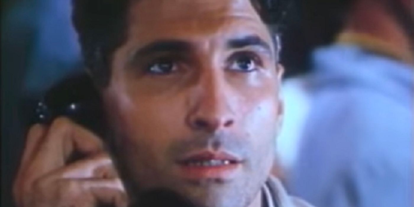 A man holds a black phone to his ear as he looks up at something in 'Day One' (1989)