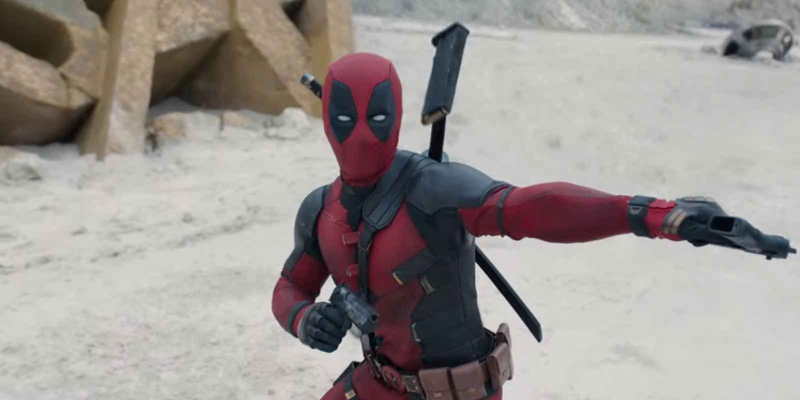 Deadpool wields two guns in a sandy setting with the Fox logo in the background. 