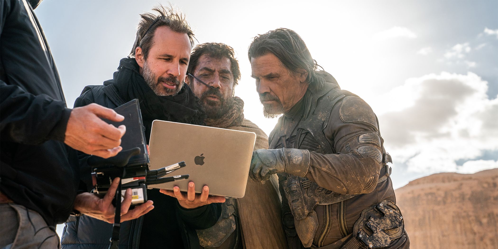 Denis Villeneuve mostrando algo a Javier Bardem y Josh Brolin en una computadora portátil en el desierto para Dune: Parte Dos