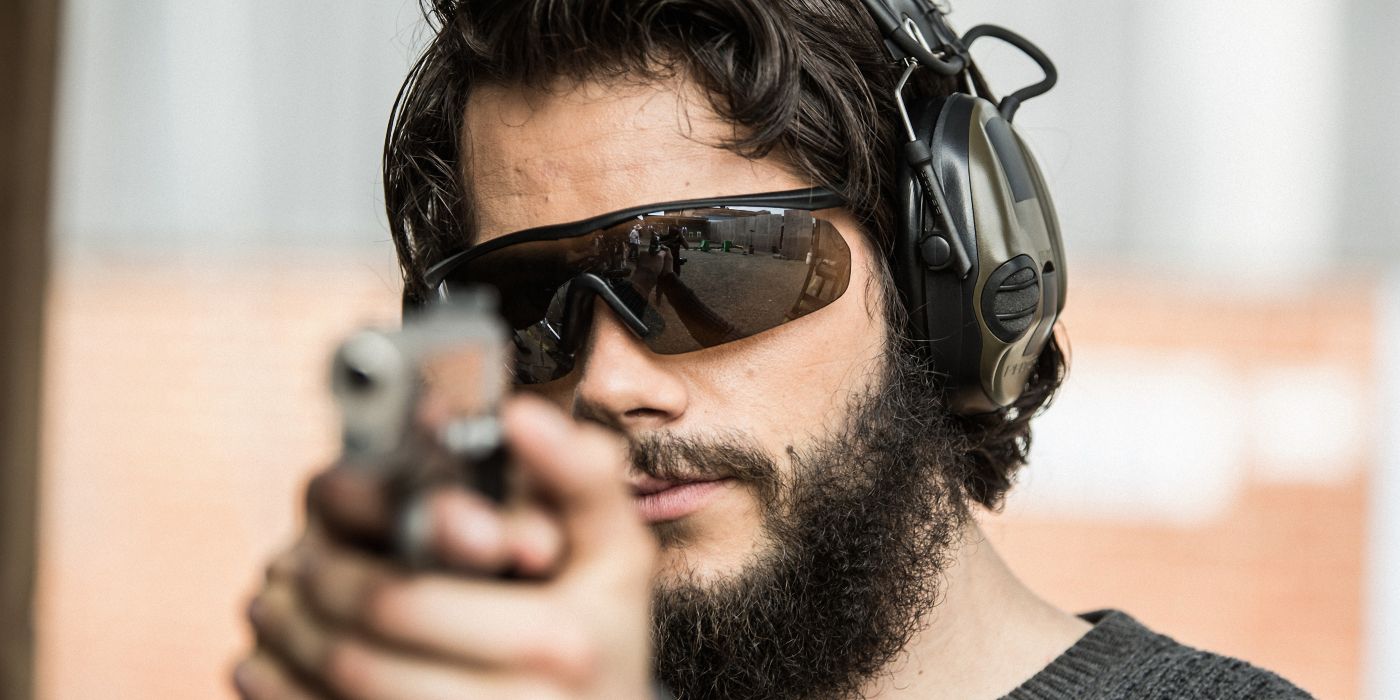 Dylan O'Brien as Mitch Rapp pointing a gun for target practice in American Assassin