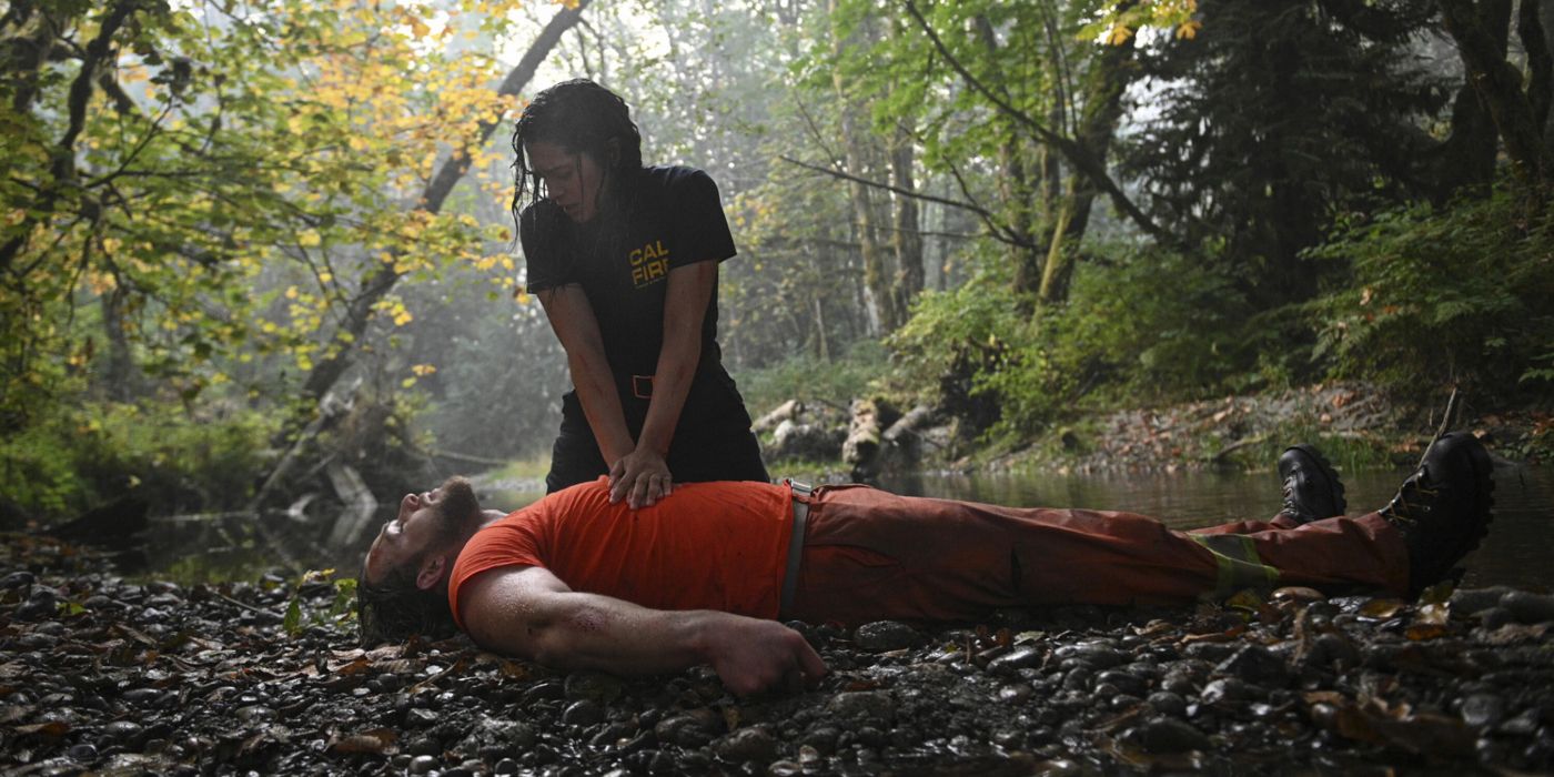 A first responder does chest compressions on an unconscious man in a wooded area in Fire Country.