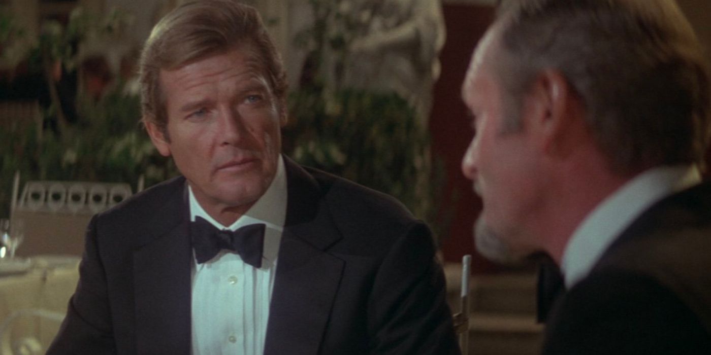 James Bond (Roger Moore) sits opposite Aristotle Kristatos (Julian Glover) wearing a tuxedo in For Your Eyes Only