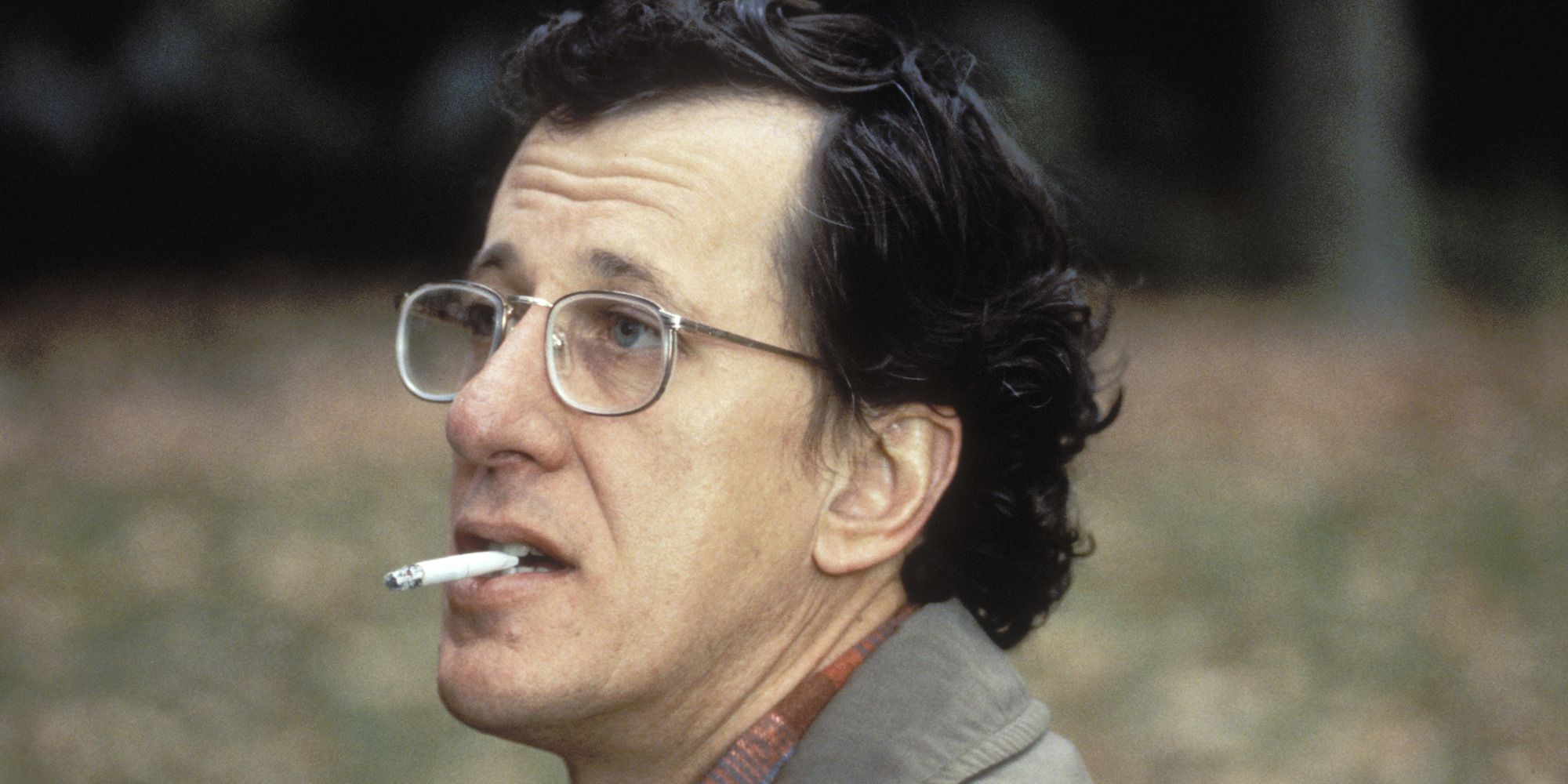 Geoffrey Rush wearing glasses smoking a cigarette out in a field in Shine