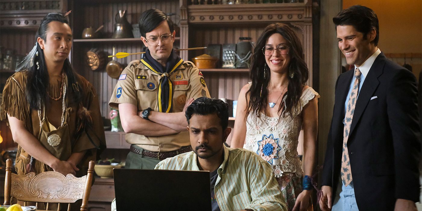 A man sits by a computer while a Lenape spirit, scout leader, hippie and Wall Street bro stand behind him.