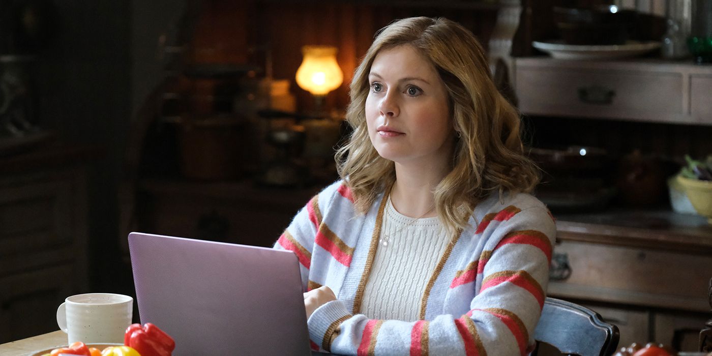 Sam (Rose McIver) sits at a table with her laptop in a scene from 'Ghosts'