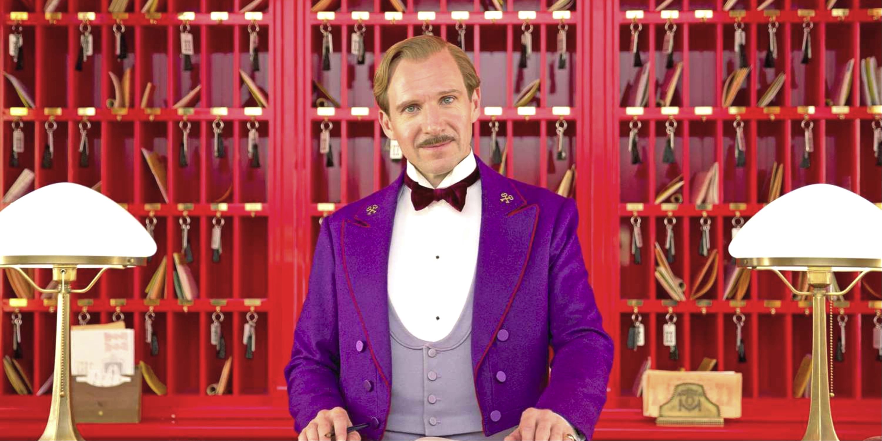 Ralph Fiennes as the concierge behind his lobby desk in Grand Budapest Hotel