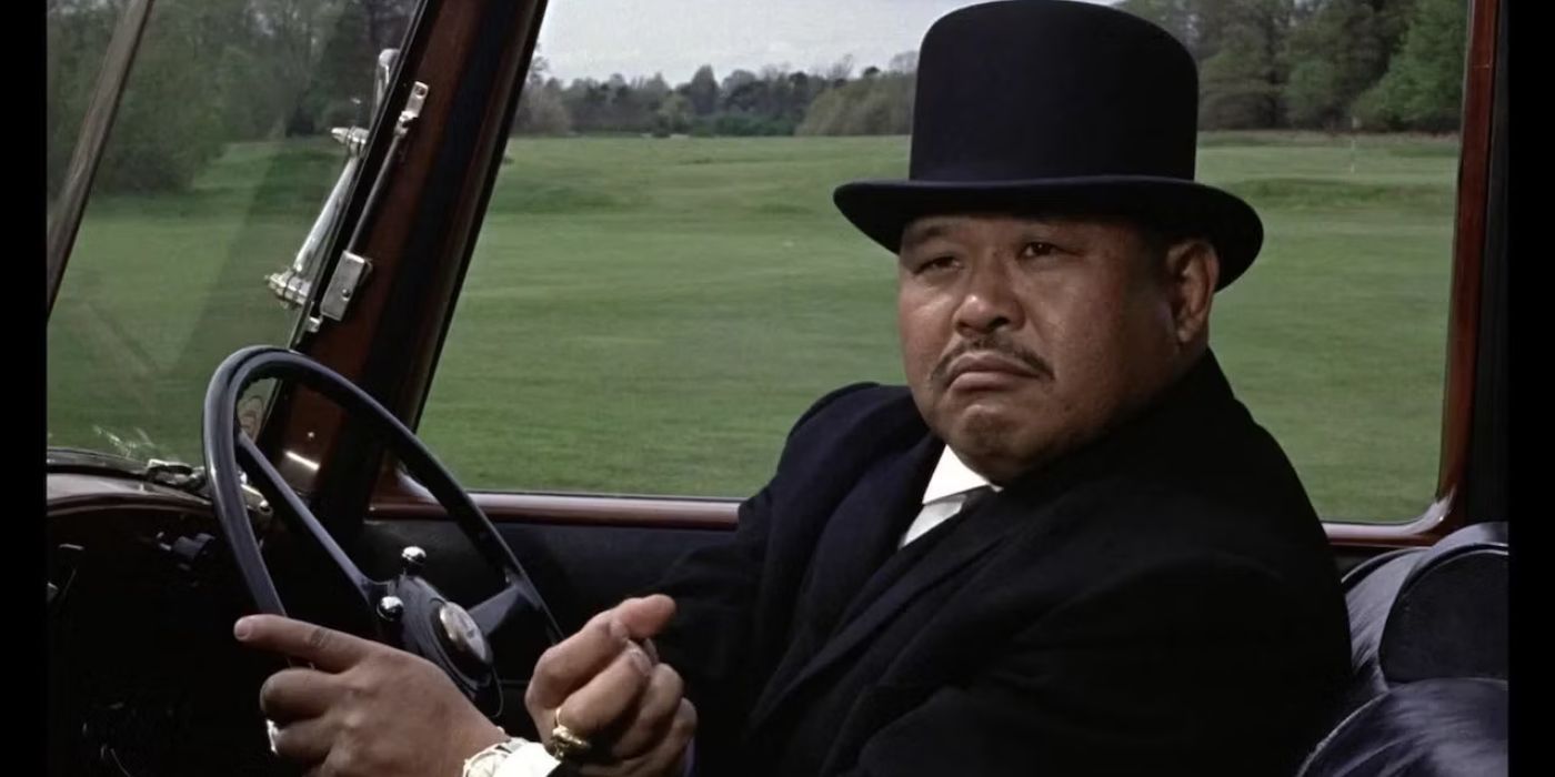 Oddjob behind the wheel of a car turning to his left in Goldfinger.