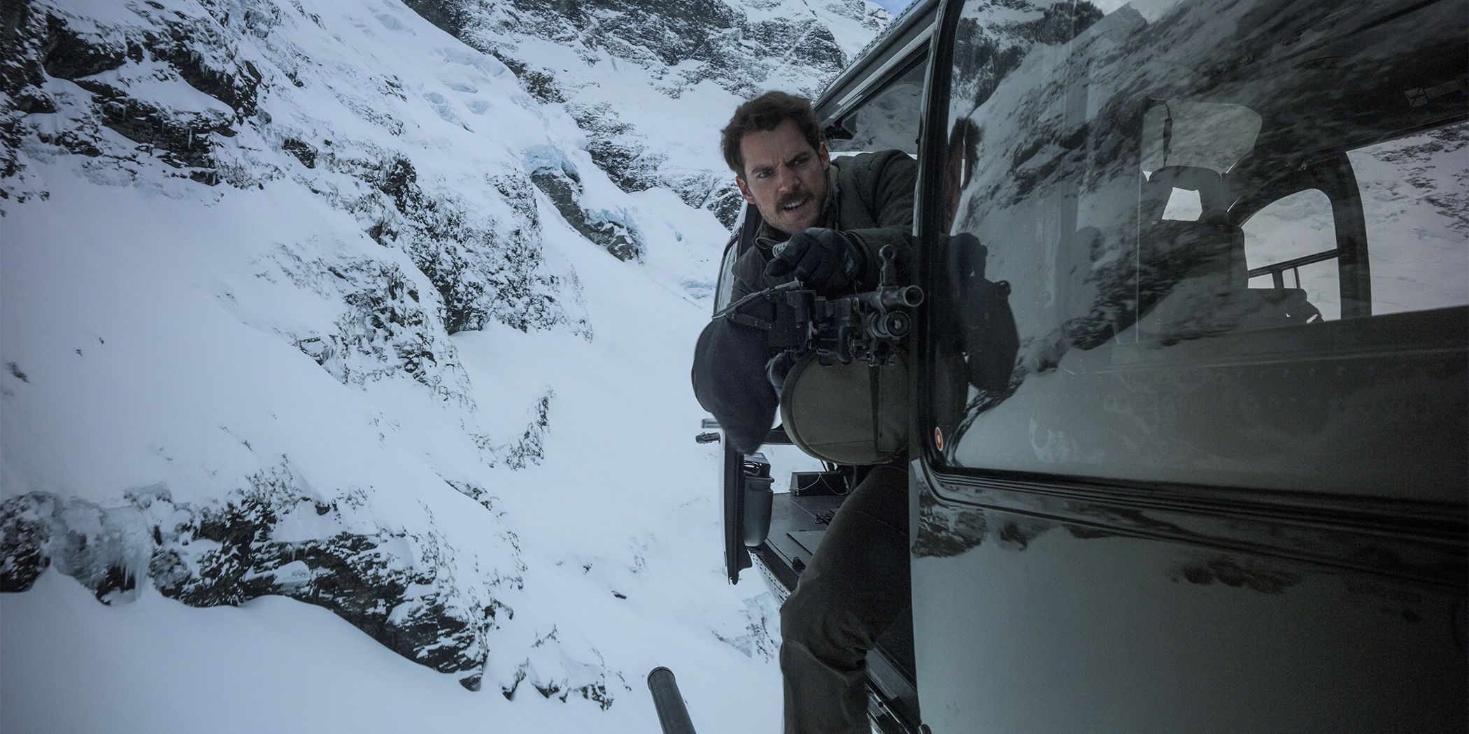 Henry Cavill leaning out of a helicopter shooting a gun in Mission: Impossible - Fallout