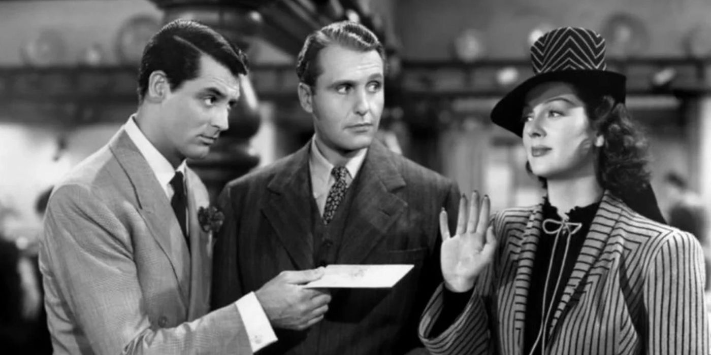 Gary Grant handing Rosalind Russell a card while Ralph Bellamy looks over at her in His Girl Friday