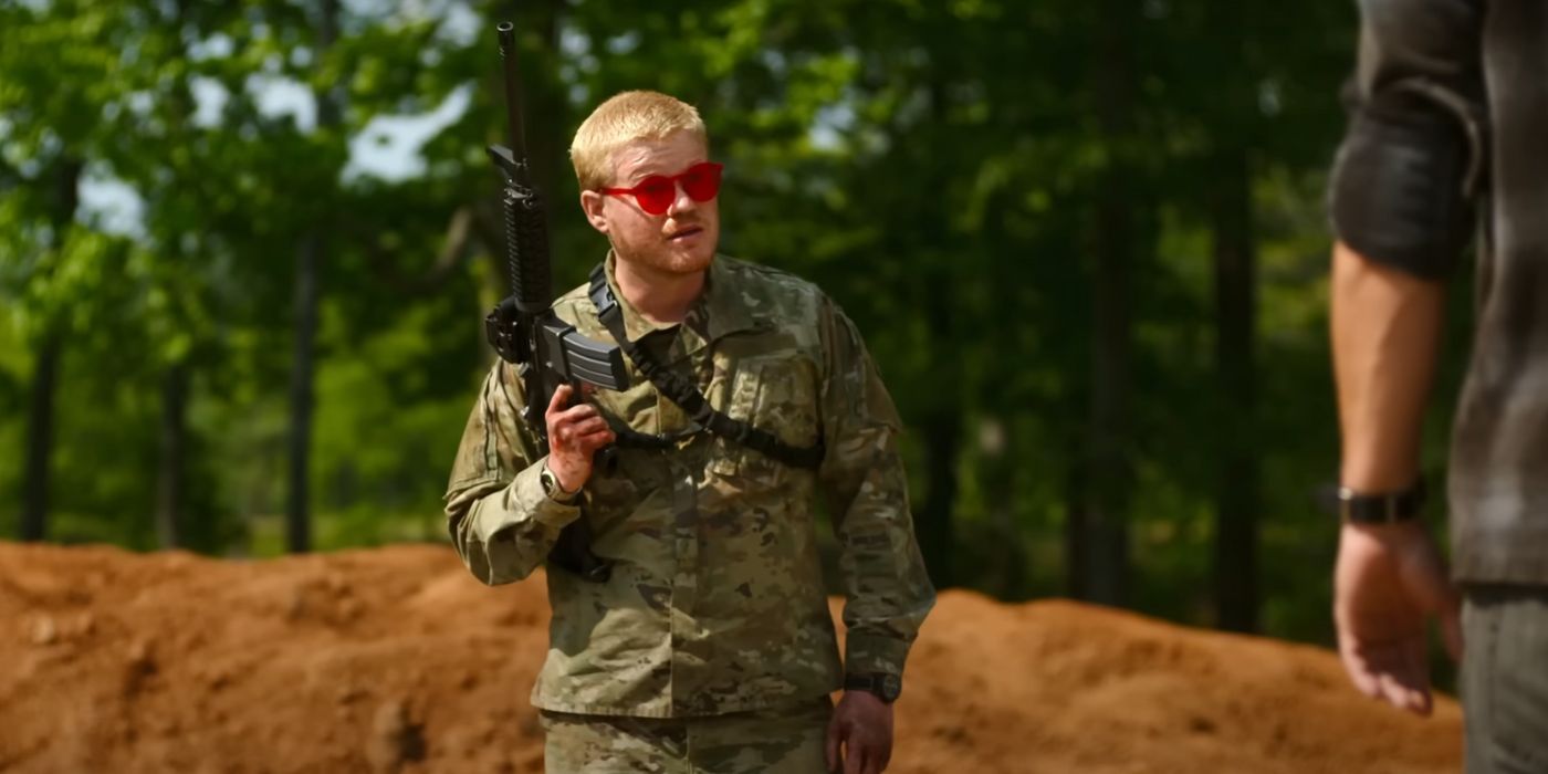 Jesse Plemons holding up a rifle and wearing red sunglasses and camouflage in Civil War.