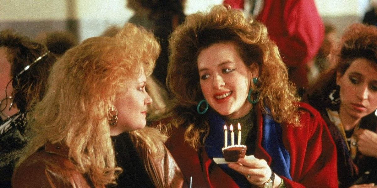 Joan Cusack hands Melanie Griffith a cupcake with lit candles in Working Girl