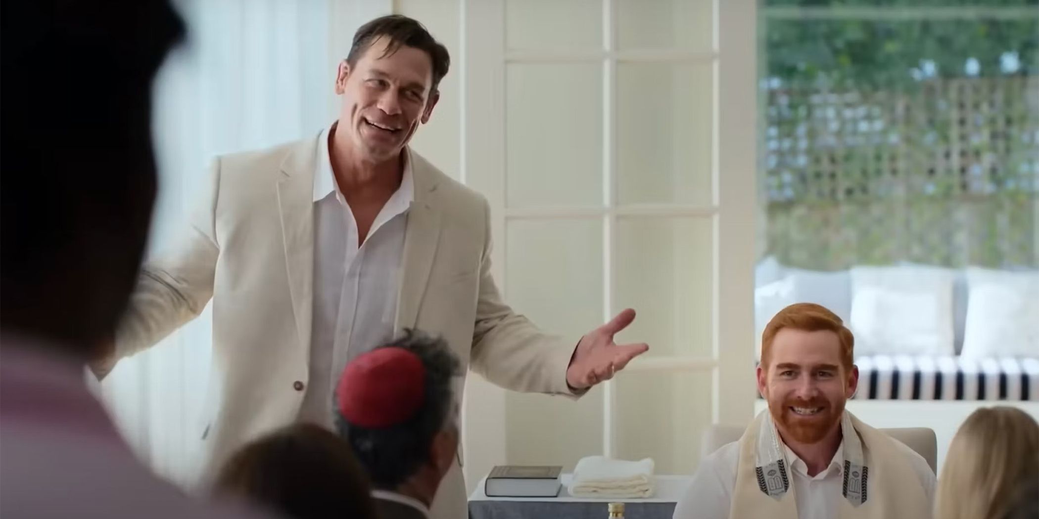 John Cena and Andrew Santino dressed in all white smiling at a banquet in a still from Ricky Stanicky