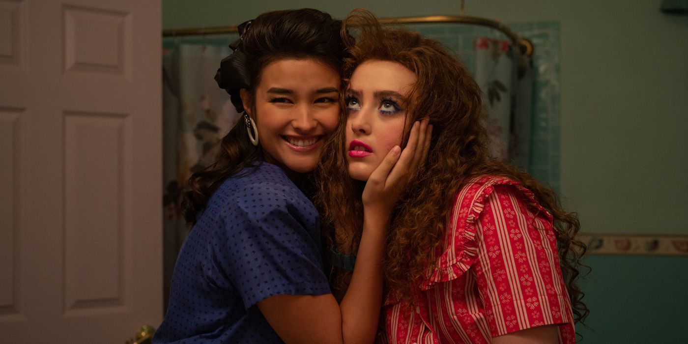 Liza Soberano as Taffy & Kathryn Newton as Lisa pressed against each other in front of a mirror in Lisa Frankenstein