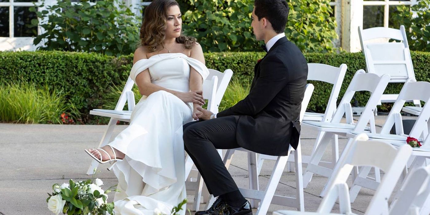 Mallory in a wedding dress Sal in a suit sitting on empty guest chairs talking in a scene from Love is Blind.
