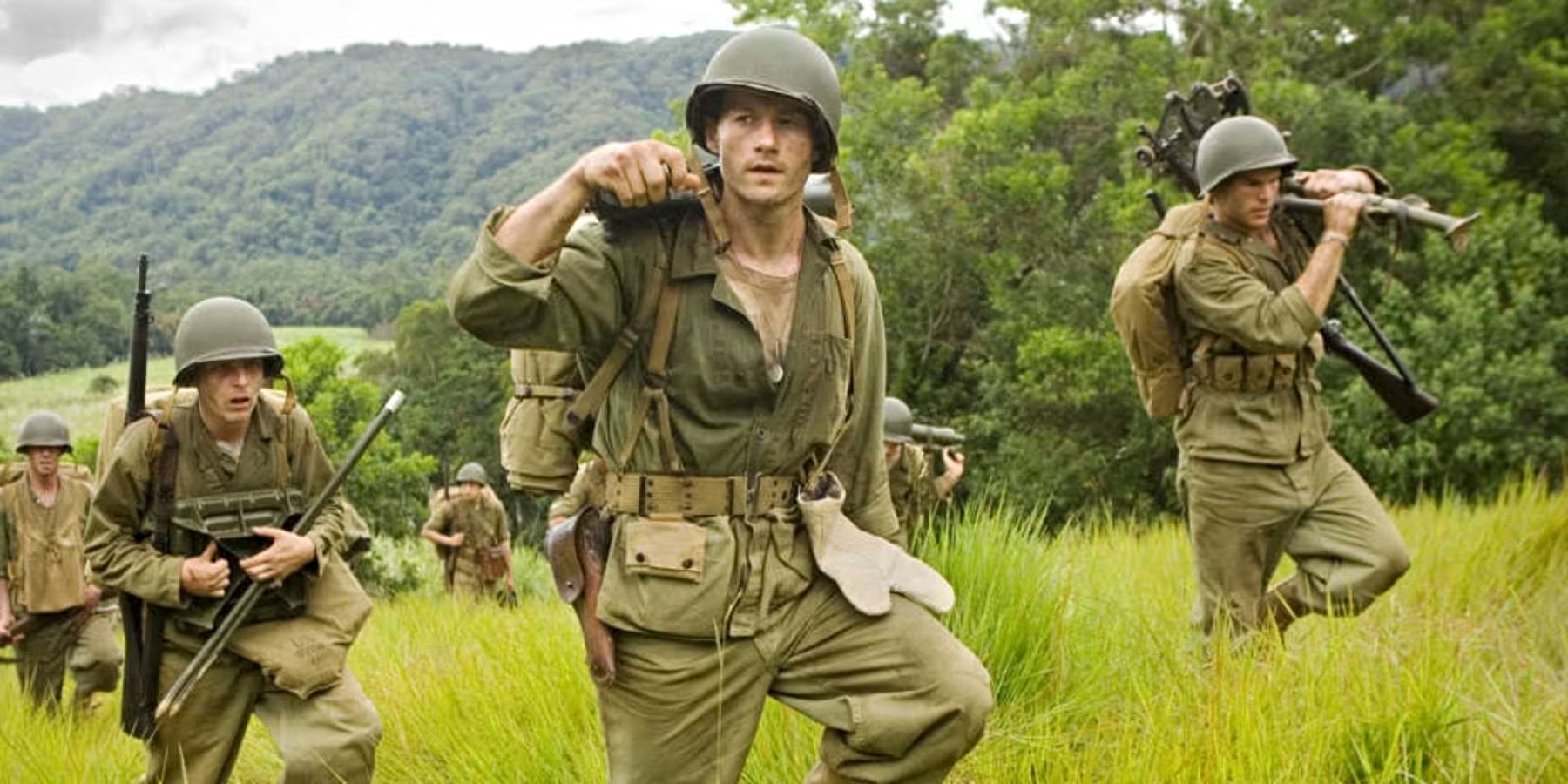 Marines carrying equipment through tall grass in The Pacific