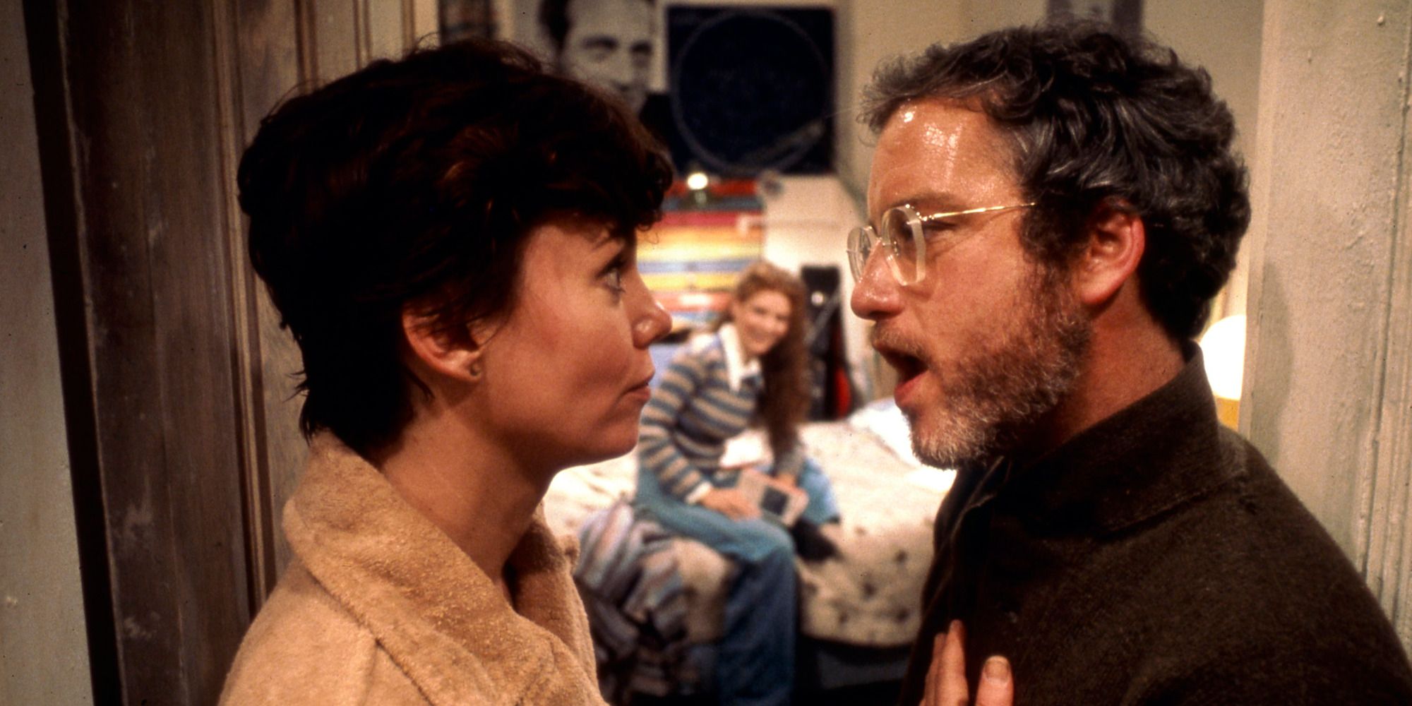 a man and woman speaking in front of a girl's bedroom, door open