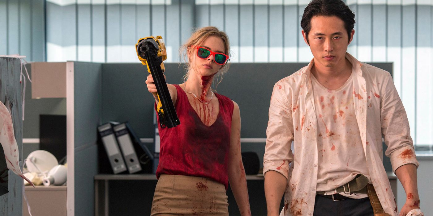 Derek (Steven Yeun) and Melanie (Samara Weaving) holding a nail gun in an office in 2017's Mayhem