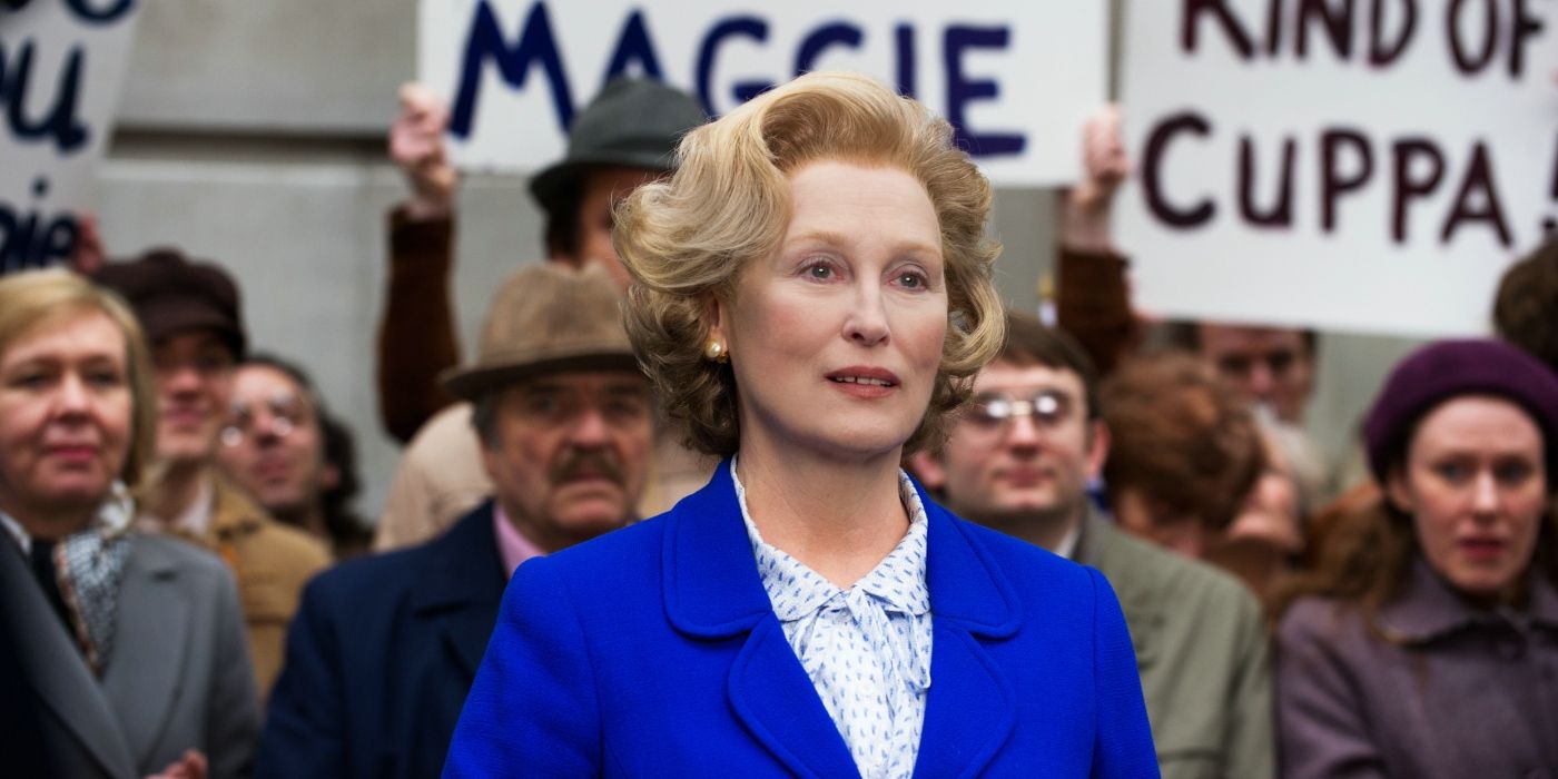 Meryl Streep as Margaret Thatcher, standing in a crowd of people holding signs in The Iron Lady