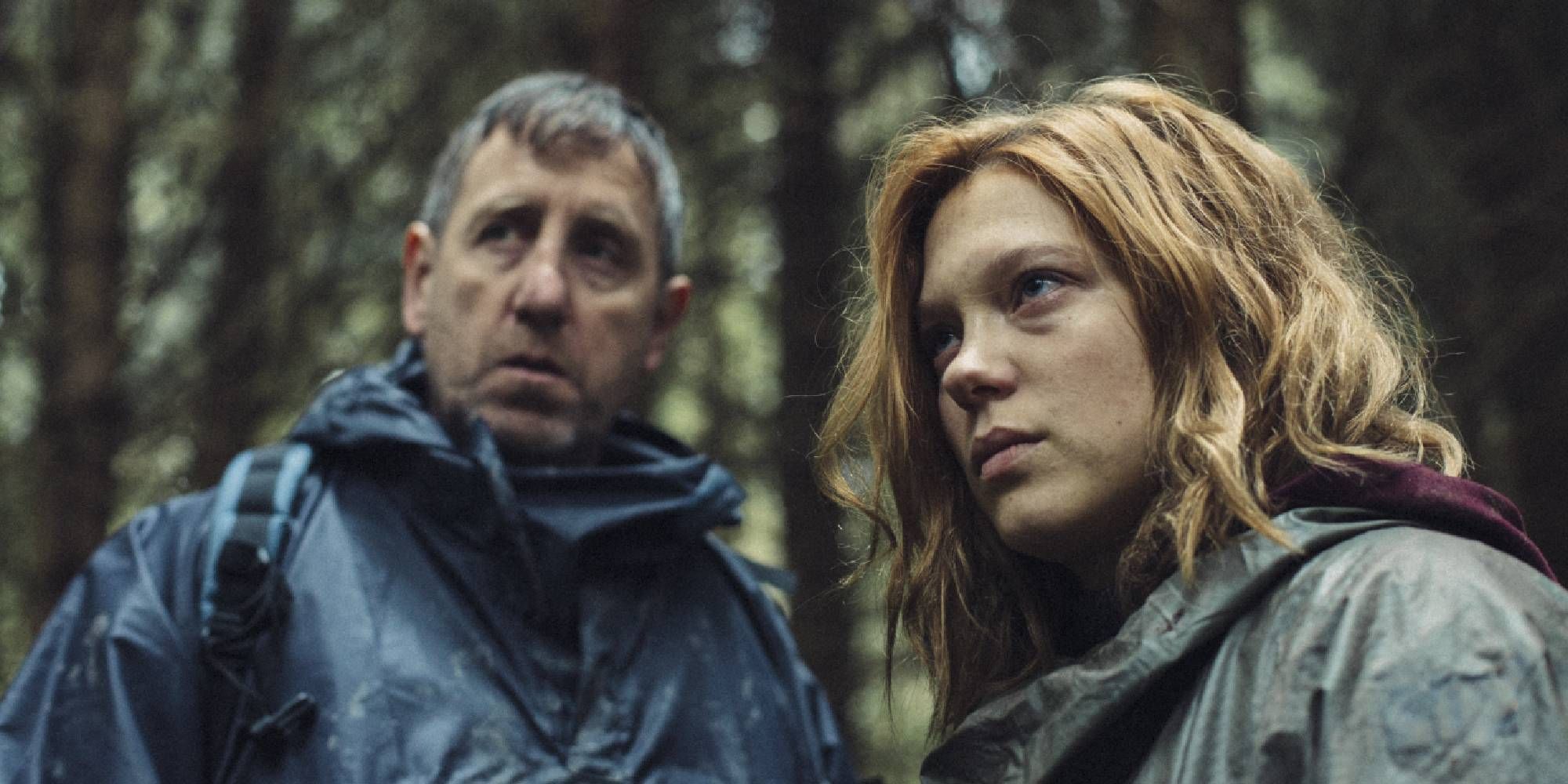 Michael Smiley and Léa Seydoux in The Lobster looking at something or someone off-camera while in the woods.
