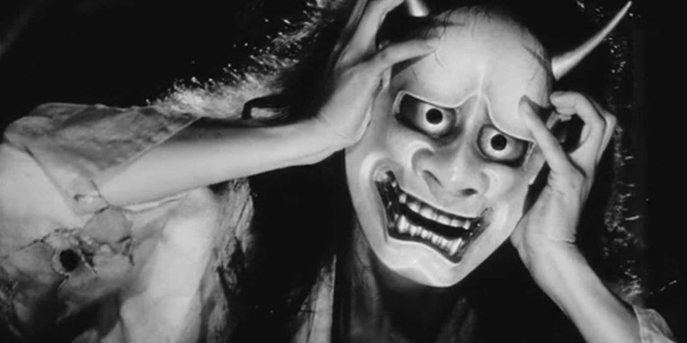 A woman wearing a demonica mask with her hands on her hair in Onibaba