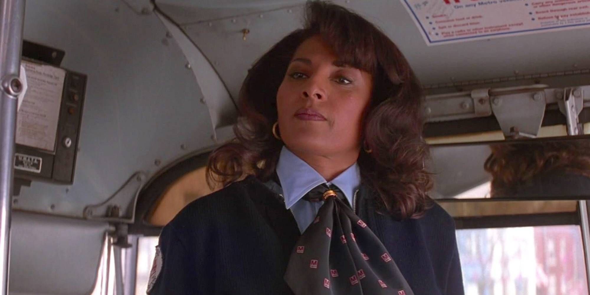 Pam Grier looking at someone off-camera while standing up inside a bus in Mars Attacks!