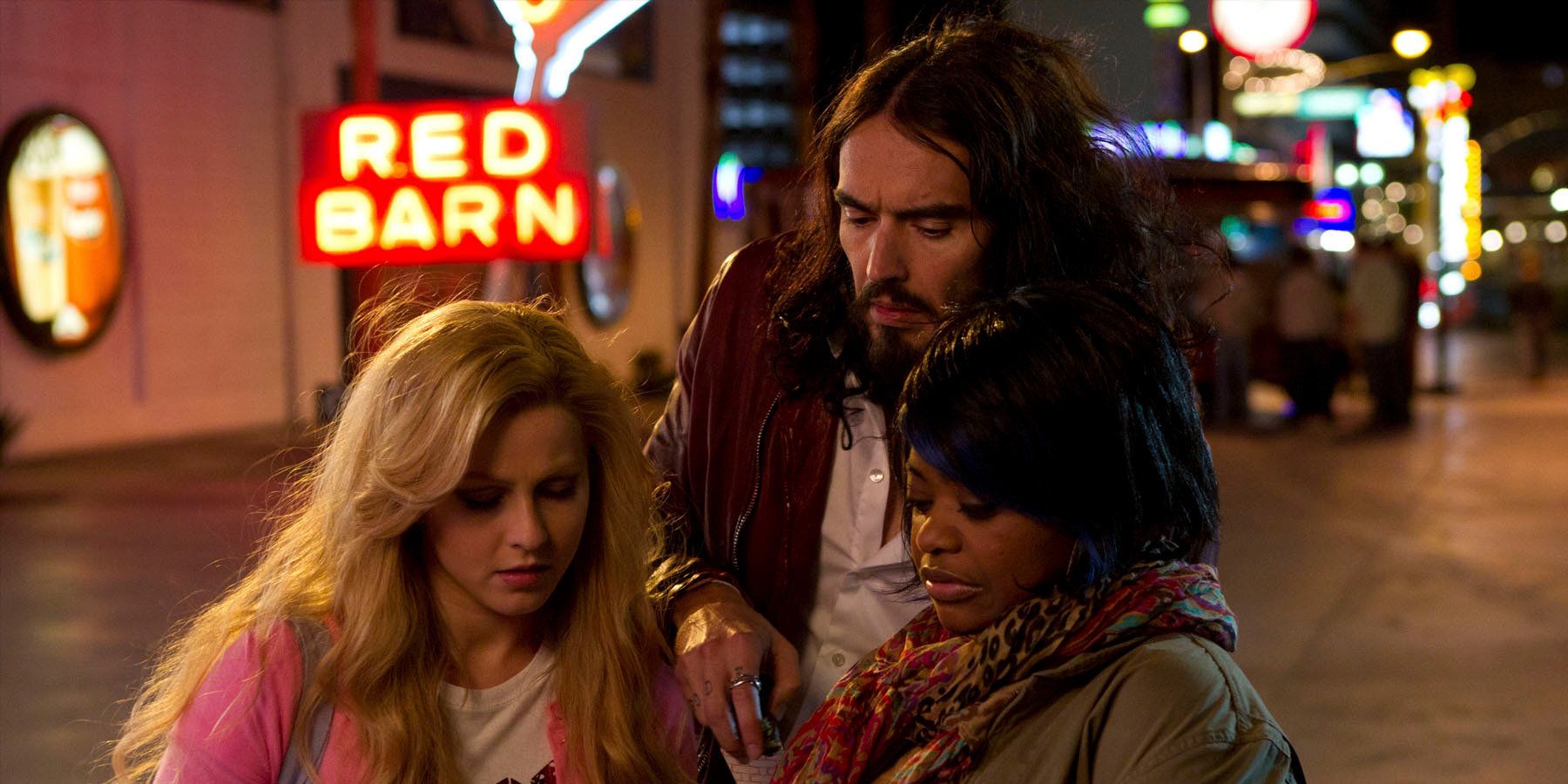 A still from the film Paradise (2013) featuring a trio of friends (including Russell Brand and Octavia Spencer) looking down at a note