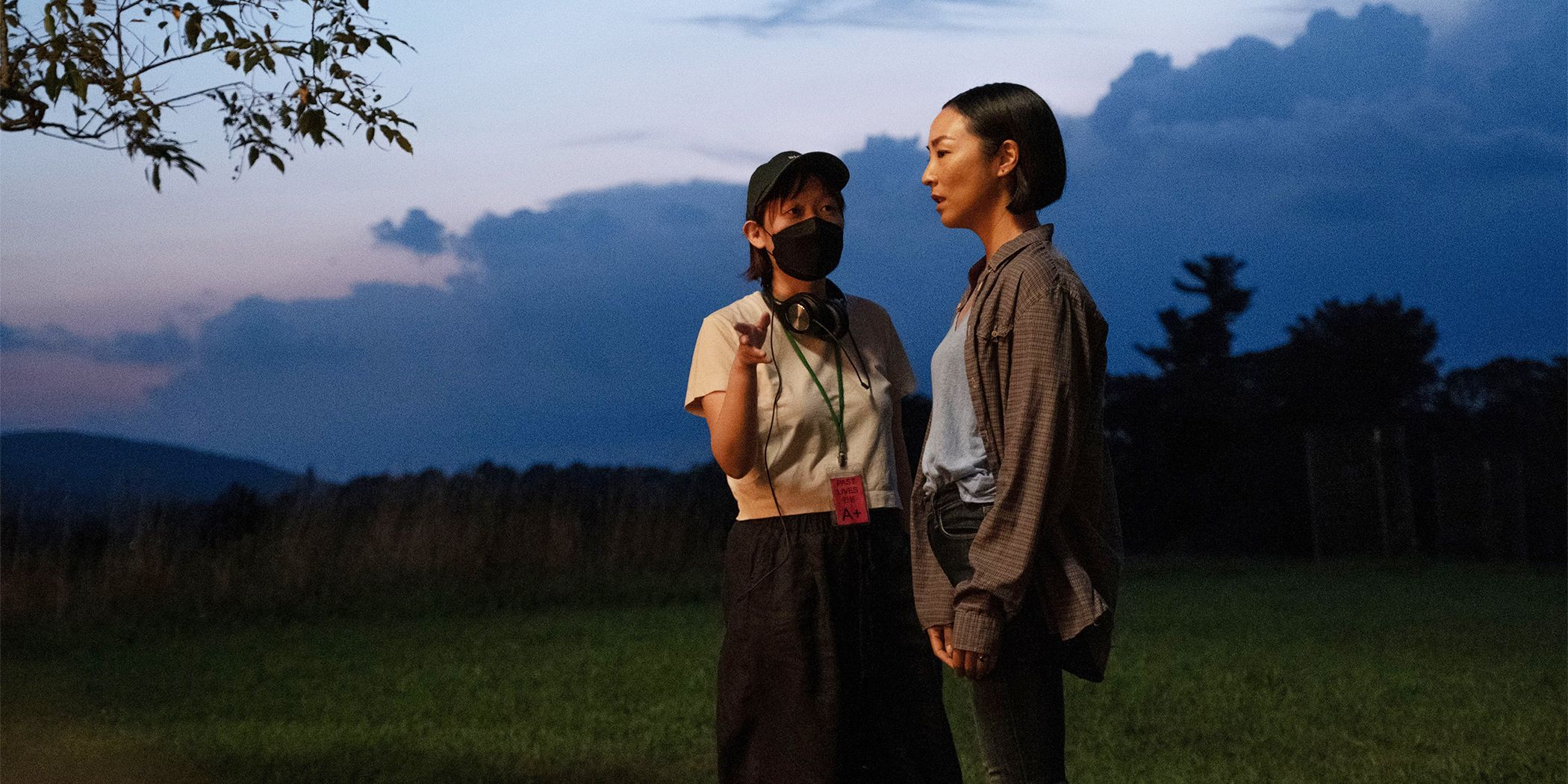 Director Celine Song speaking to Greta Lee as Nora in a field at sunset for Past Lives